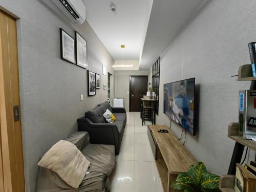 a living room with a couch and a table at Cozy 1BR with Balcony and Netflix in Uptown BGC in Manila