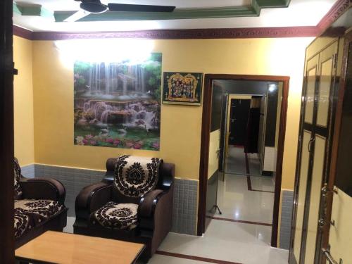 a living room with two chairs and a painting on the wall at Kodali Homestays in Bhadrāchalam