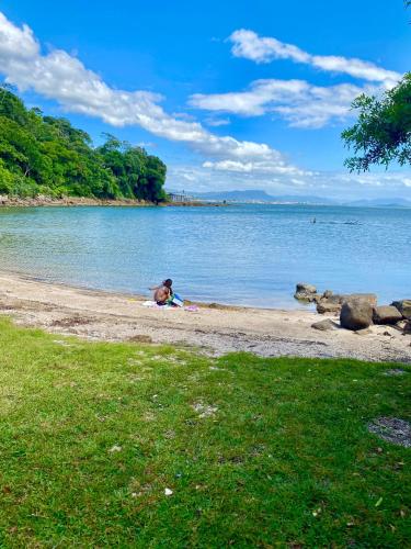 a person sitting on the shore of a body of water at Double Deck - Linda vista com Jacuzzi in Palhoça
