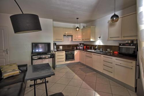 Il comprend une cuisine avec des placards blancs, un canapé et une télévision. dans l'établissement Marina les calanques, à Marseille