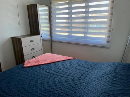 a bedroom with a blue bed and a window at Casa Familiar Estepa Patagónica in Puerto Natales
