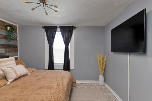 a bedroom with a bed and a flat screen tv at Summerset Cottage Atlanta in Atlanta
