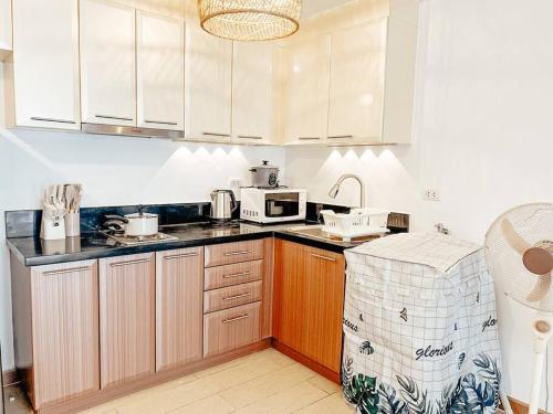une cuisine avec des armoires blanches et un micro-ondes dans l'établissement Venice Luxury Residences Studio McKinley Hill, à Manille