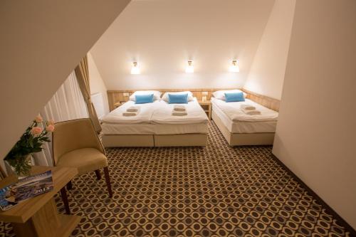 a hotel room with two beds and a chair at Borowy Dwór- Biznes, Spa & Fun in Szaflary