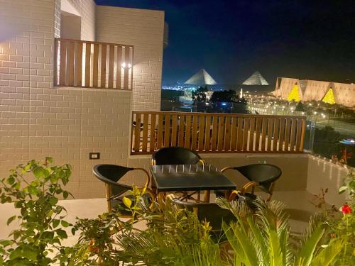a patio with a table and chairs on a balcony at night at New Museum Guest House, Pyramids View in Cairo