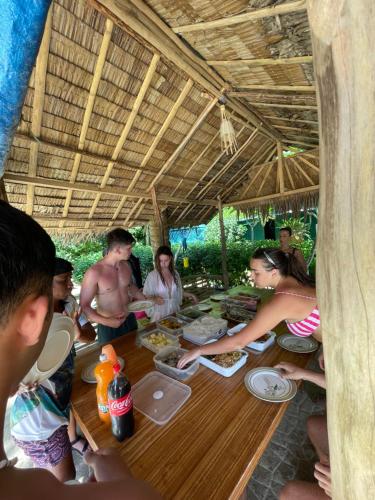 a group of people sitting around a table eating food at Hidden of Cailan Extension Transient House in El Nido