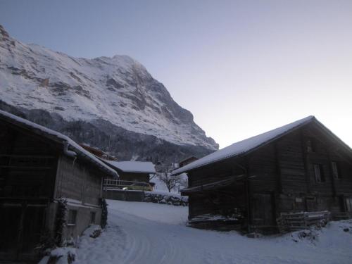 a snow covered barn with a mountain in the background at Chalet Bärgblick in Grindelwald