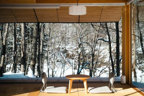 une pièce avec une grande fenêtre avec une table et des chaises dans l'établissement Moving Inn Tokachi Kitanomori, à Taiki