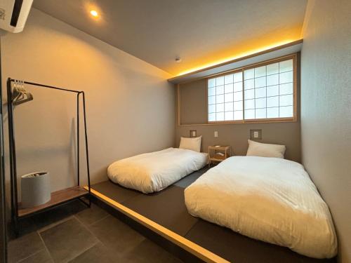 Dos camas en una habitación pequeña con ventana. en Beach enzi ビーチ エンジ, en Sanuki