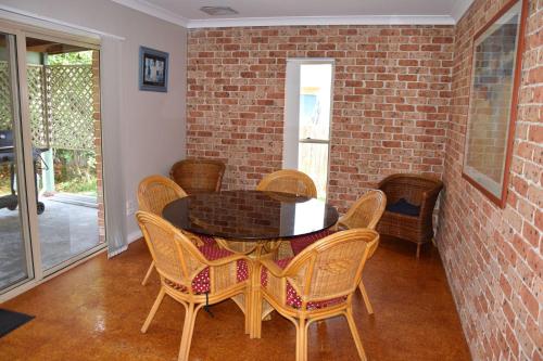 Un comedor con una mesa y sillas y una pared de ladrillos. en Parkview Lodge - Bring your own linen., en South West Rocks