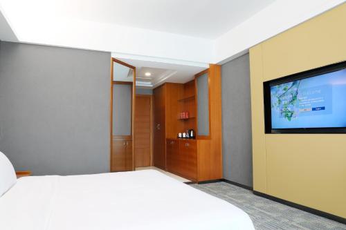 a hotel room with a bed and a flat screen tv at 空港别墅酒店广州白云国际机场店 in Guangzhou
