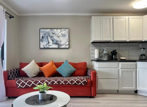 a living room with a red couch with colorful pillows at Cozy Galveston Beach Front Condo in Galveston