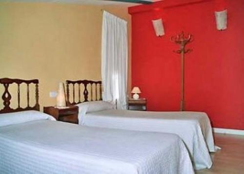 two beds in a room with red walls at Casa Rural Jose Trullenque in Morella