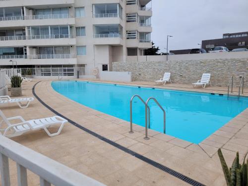 Una gran piscina con sillas al lado de un edificio. en Departamentos La Serena Vista, en La Serena