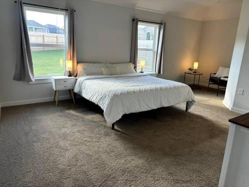 a bedroom with a large bed and two windows at Quite big home near Tesla & COTA in Del Valle