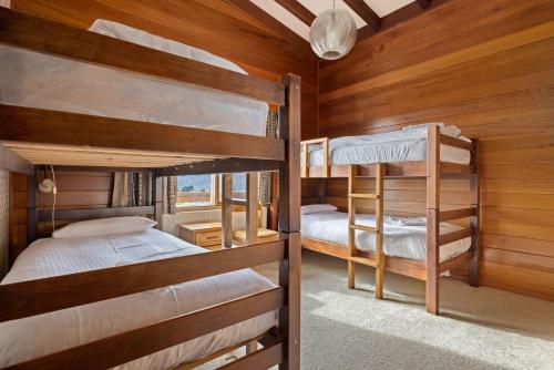two bunk beds in a room with wooden walls at Elvira Ski Haus in Jindabyne