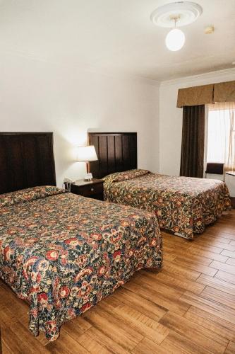 エンセナダにあるHotel del valleのベッド2台とランプが備わったホテルの部屋
