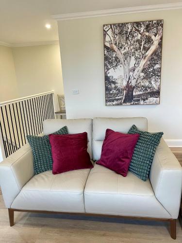 a white couch with red and blue pillows on it at Nature at your Doorstep in Katoomba
