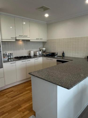 a kitchen with white cabinets and a granite counter top at Nature at your Doorstep in Katoomba
