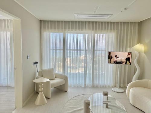 a white living room with a couch and a chair at Le Bleu Naksan by Orot in Yangyang