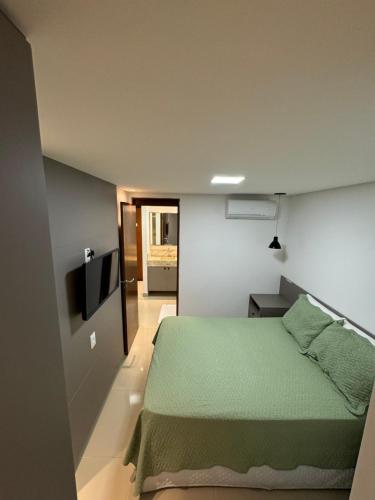 a bedroom with a green bed and a flat screen tv at Apartamento em João Pessoa (Miramar) in João Pessoa