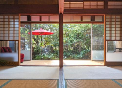 an open door with a red umbrella in a room at 古民家おにぎり in Otsu