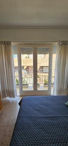 Un dormitorio con grandes ventanales y una alfombra azul. en Alquiler en Varese, Mar del plata a pasos del mar, en Mar del Plata