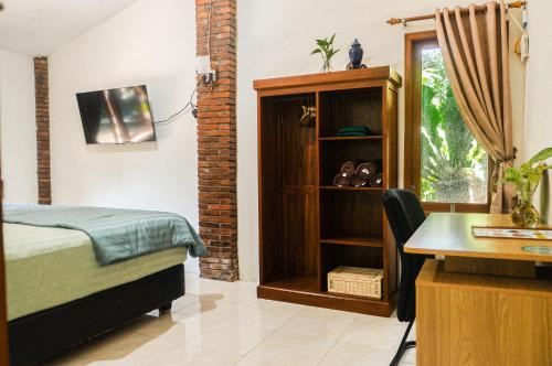 a bedroom with a bed and a desk and a desk at Omah Ralin Family Homestay with Spacious Joglo House in Timuran
