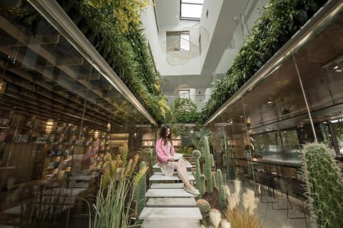 a woman sitting on the stairs in a building with plants at iTree Guanhu Academy Huizhou West Lake in Huizhou