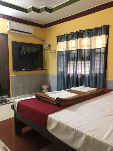 a bedroom with a bed and a flat screen tv at Kodali Homestays in Bhadrāchalam