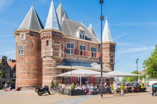 a large brick building with people sitting outside of it at Houseboat studio with canalview and free bikes in Amsterdam
