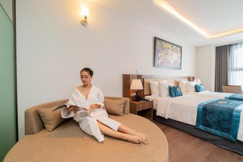 a woman sitting on a bed in a hotel room at Gonsala Hotel Nha Trang in Nha Trang
