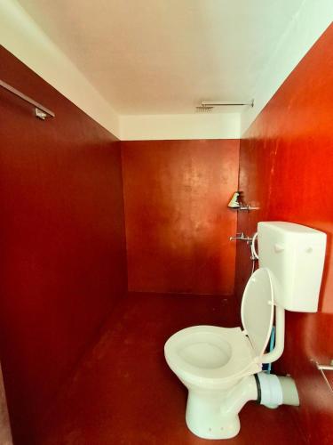 a bathroom with a white toilet in a red room at Sadhana on the beach in Alleppey