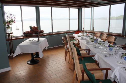 a dining room with tables and chairs and windows at Crinan Hotel in Crinan