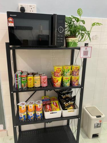 a shelf with a microwave and some food at Cozy homestay in Mersing
