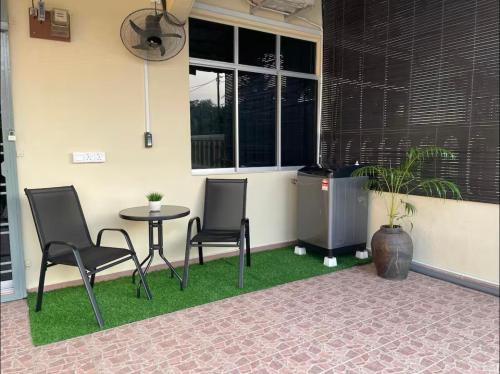 a patio with two chairs and a table and a window at Cozy homestay in Mersing