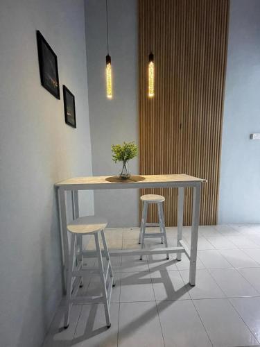 a table and two stools with a potted plant on it at Cozy homestay in Mersing