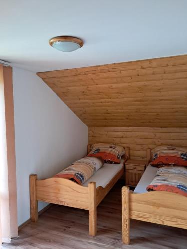 Habitación con 2 camas individuales y paredes de madera. en Dolinka Holiday Home, en Levoča