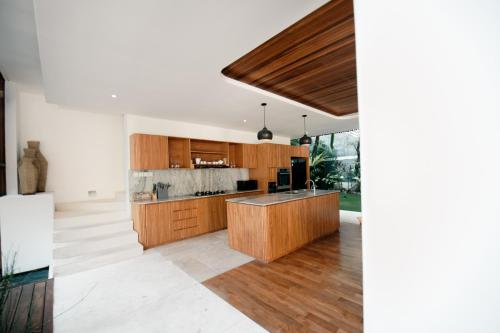 an open kitchen with wood cabinets and a island at Seminyak Villa Paya paya Luxury near beach-Potato Head in Seminyak