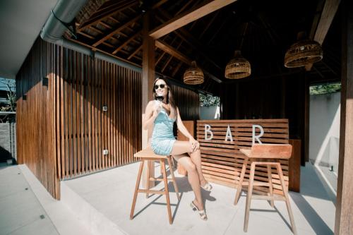 a woman in a blue dress sitting on a chair at Seminyak Villa Paya paya Luxury near beach-Potato Head in Seminyak
