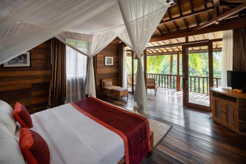 a bedroom with a canopy bed and a balcony at Pertiwi Bisma 1 in Ubud