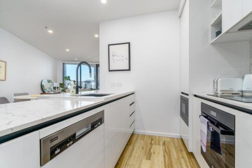 a white kitchen with a sink and a counter at Serene 2BR Apt in the Radiant City of Civic - Hosted by Canstay in Canberra