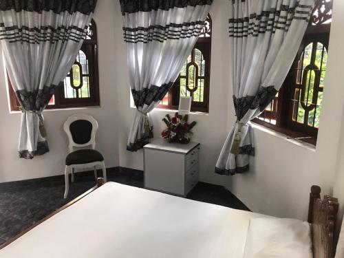 a bedroom with a bed and two windows at Kingz and Queenz - Negombo in Negombo