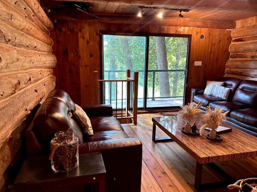 ein Wohnzimmer mit Ledersofa und einem Tisch in der Unterkunft John Wayne Cedar Oasis in Cookstown