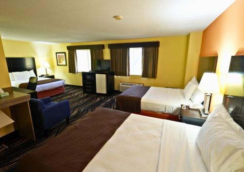 a hotel room with two beds and a chair at Rock Island Inn & Suites Streator , IL in Delbert Egan Housing Project