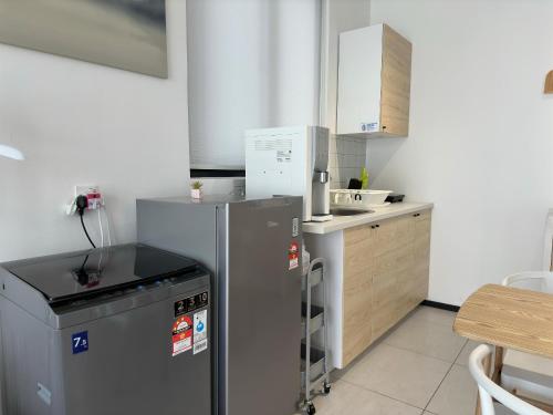 a small kitchen with a refrigerator and a sink at Cozy Urban Suites Georgetown View in Jelutong