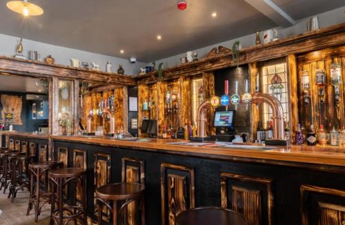 a bar with wooden cabinets and bar stools at The Rhu Inn in Rhu