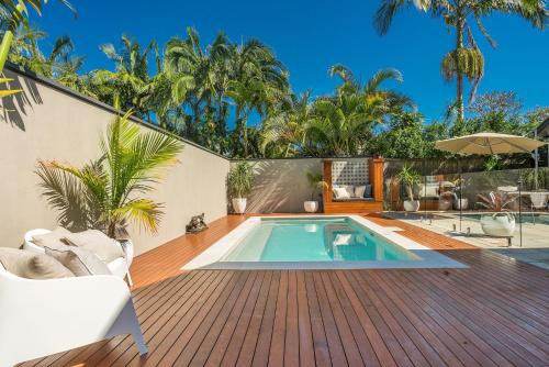 a swimming pool on a wooden deck next to a house at 3 Little Pigs in Byron Bay