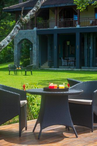 a table and chairs on a deck with a yard at Kandy Dendrobium House in Kandy