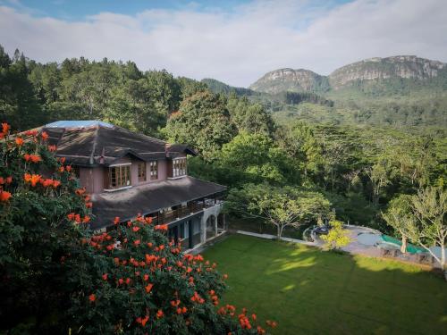 a house with a garden and mountains in the background at Kandy Dendrobium House in Kandy